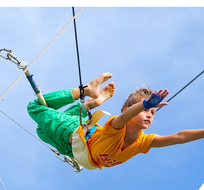 Young guest mid-swing on a flying trapeze rig at the MACA academy — Phuket, Thailand — MACA flying trapeze rig
